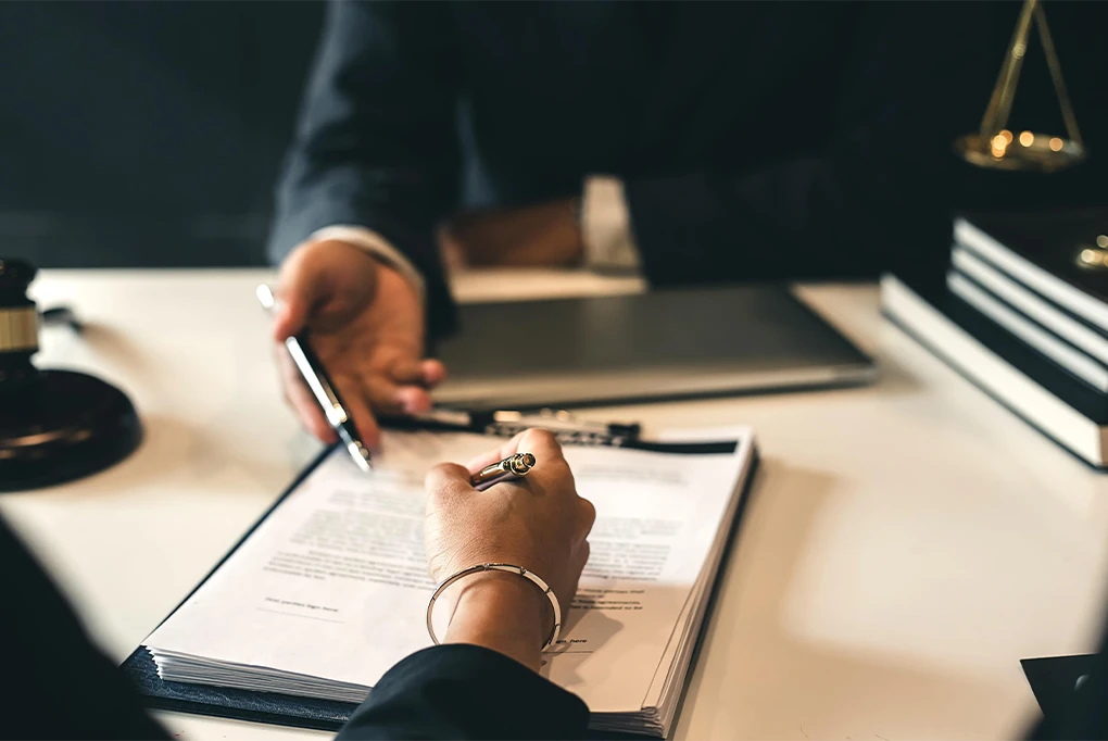A lawyer and client reviewing and signing legal documents at a desk, representing how Parent Link supports attorneys and mediators with organized co parenting records.